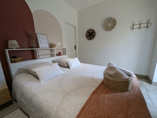 Chambre moderne à La Cour d'Hortense avec lit king-size, mur accent bordeaux et décoration murale tressée