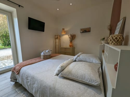 Chambre moderne à La Cour d'Hortense avec lit queen-size, télévision écran plat, vue sur le jardin et mobilier contemporain
