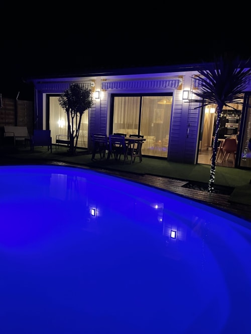 Vue nocturne de la piscine illuminée de la Villa Eden Bleu avec bâtiment d'hébergement moderne éclairé à Biscarrosse