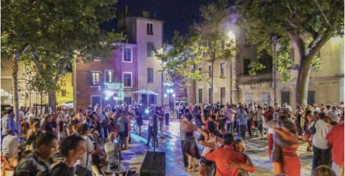 Lively outdoor evening gathering in Boissieres village square with colorful buildings and festive atmosphere