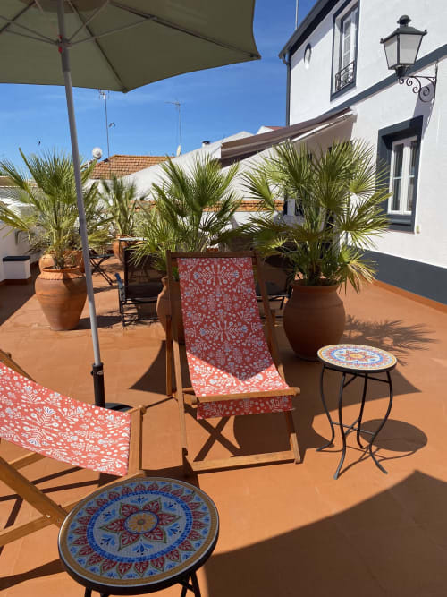Sunny rooftop terrace at Patio Da Villa with lounge chairs, potted palms, umbrella, and decorative tables in Coruche