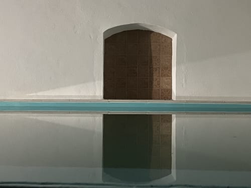 Minimalist pool view at Patio Da Villa guesthouse in Coruche, Portugal, with arched doorway and turquoise water reflection