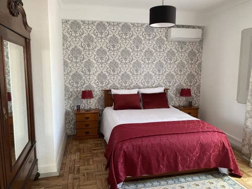 Elegant bedroom at Patio Da Villa guesthouse in Coruche with burgundy accents, damask wallpaper, and wooden nightstands