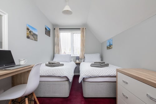 Cornish Holiday - 100 Hengar Manor. Upstairs twin bedroom with two single beds. desk, laptop, chair and chest of drawers. Complimentary towels.