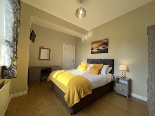 Room 6 at Steeple View B&B Donegal features a black bed with yellow accents, wooden floors, and modern ensuite amenities.