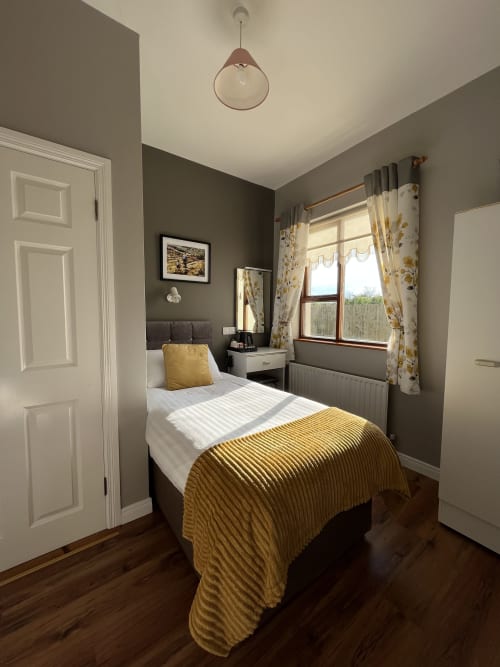 Room 7 at Steeple View B&B in Donegal featuring a single bed with yellow bedding, gray walls, and en-suite bathroom
