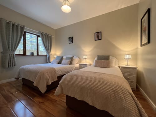 Bright twin bedroom at Steeple View B&B Guesthouse Donegal with two beds, wooden floors, and warm lighting