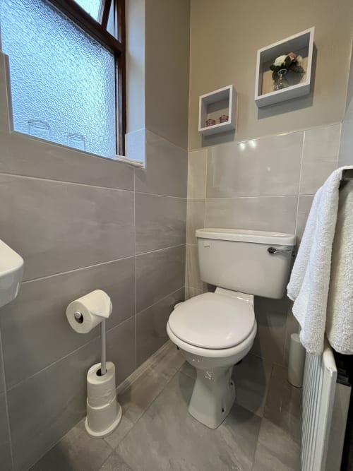 Modern ensuite bathroom at Steeple View B&B Guesthouse in Donegal with toilet, towel rack, and wall shelves