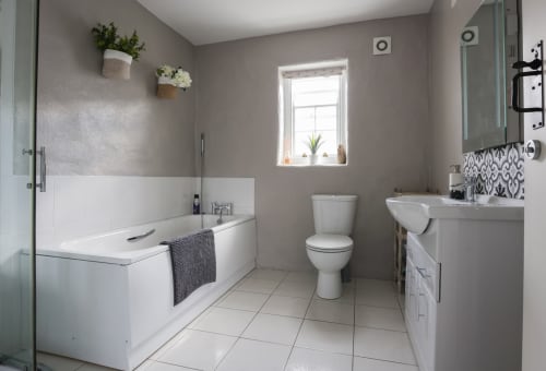 Modern bathroom at Ballymultimber Cottages with white bathtub, toilet, sink vanity, and heated towel rack in Limavady