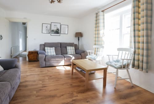 Bright living room in The Barn cottage at Ballymultimber, Limavady, with sofa, wooden table, and mountain views