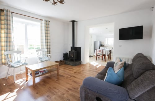 Bright open-plan living area in Ballymultimber Cottages barn cottage, Limavady, with wood floors, cozy seating, and wood