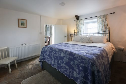 Bright bedroom at Ballymultimber Cottages in Limavady with blue patterned bedding, metal bed frame, and countryside views