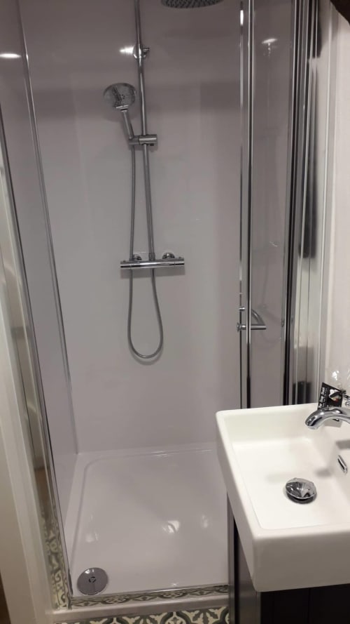 Modern shower enclosure with glass doors and rainfall showerhead in Cissy's Cottage at Ballymultimber, Limavady