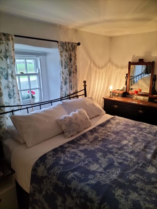Cozy bedroom at Cissy's Cottage in Limavady with metal bed frame, white pillows, patterned bedspread, wooden dresser with