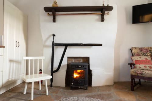 Cozy sitting area in Cissy's Cottage at Ballymultimber with white chair, fireplace, and floral armchair