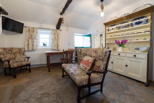 Cissy's Cottage sitting area at Ballymultimber in Limavady with floral furniture, blue china dresser, and mountain views
