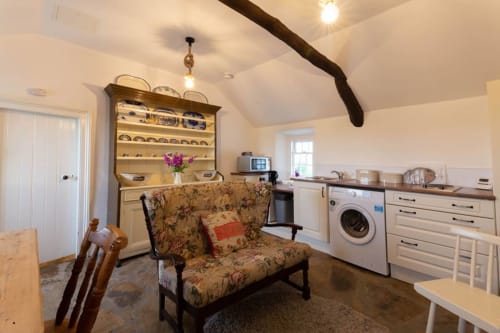 Cissy's Cottage living area with floral sofa, kitchenette, and dining space at Ballymultimber, Limavady