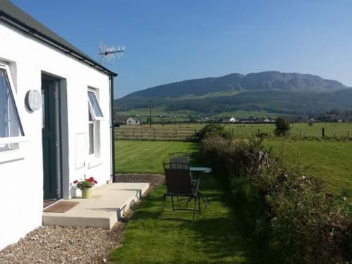 White cottage at Ballymultimber with garden seating overlooking green fields and mountains near Limavady