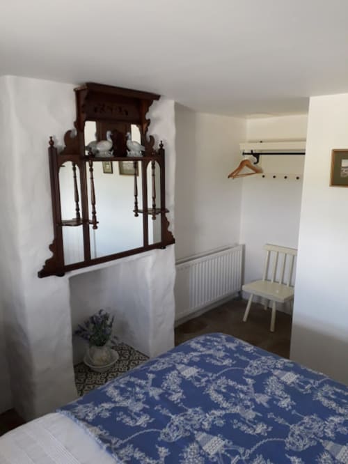 Cozy bedroom at Cissy's Cottage in Limavady with blue patterned bedding, antique mirror, white walls, and sitting area