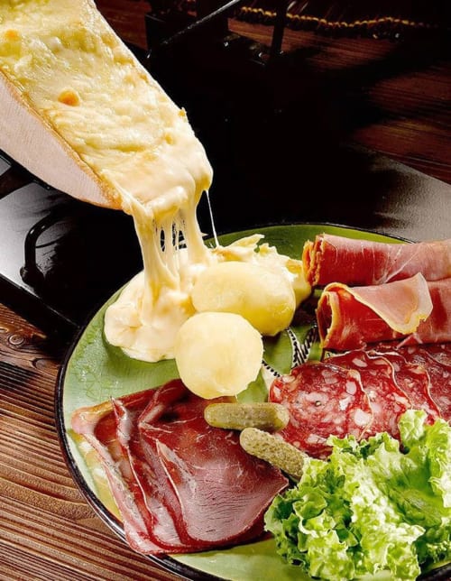 Fromage à raclette fondu raclé sur assiette avec charcuteries et cornichons à la Villa Valtin B&B au Valtin, France