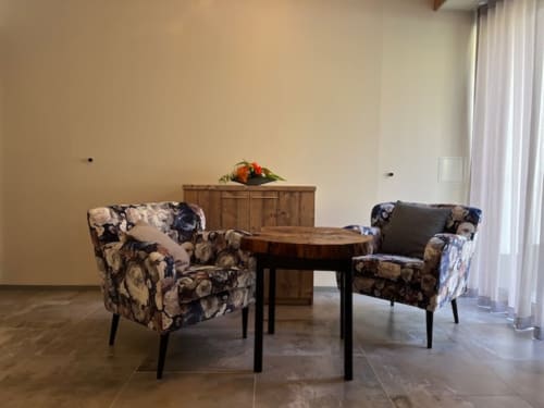 Coin salon raffiné à la Villa Valtin avec fauteuils fleuris, table ronde en bois et vue sur les montagnes