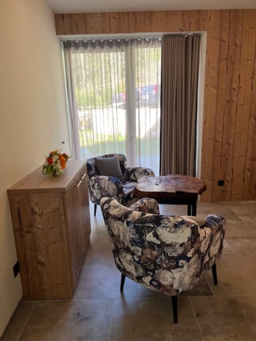 Chambre Villa Valtin avec fauteuils à motifs, mobilier en bois et vue sur les montagnes depuis les portes-fenêtres du balcon