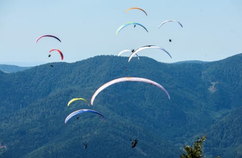Plusieurs parapentistes s'envolent au-dessus des montagnes boisées près de Villa Valtin au Valtin, France