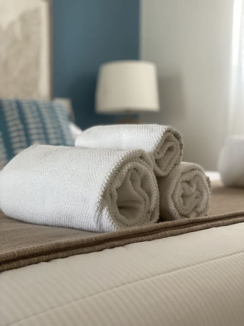 Aufgerollte weiße Handtücher auf dem Bett im Verdolivo B&B in Sale Marasino, Italien