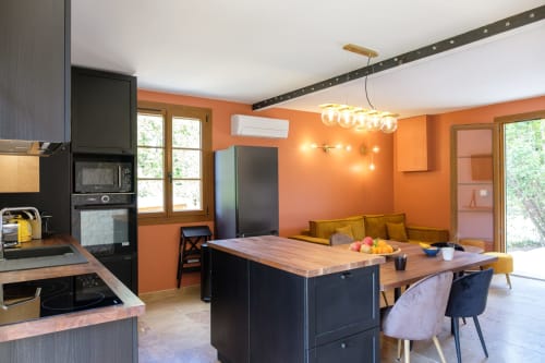 Pièce à vivre confortable avec canapés, murs en pierre et vue sur le jardin.