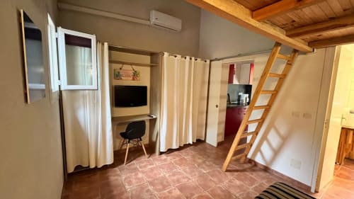 Mini villa mezzanine au Maquis Plage : séjour avec TV, bureau, kitchenette et échelle vers la mezzanine