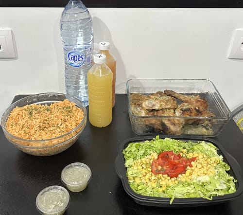 Plateau repas au Kaz A Bibi : riz, poulet grillé, salade, jus et eau sur table noire