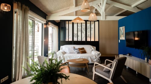 Modern bedroom at Villa Eden Bleu with bed, blue accent wall, wicker pendants, and patio access in Biscarrosse
