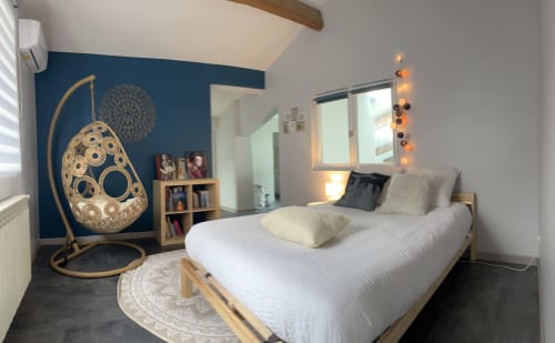 Modern villa bedroom at La Conciergerie De Franck with rattan swing chair, blue accent wall, and contemporary décor