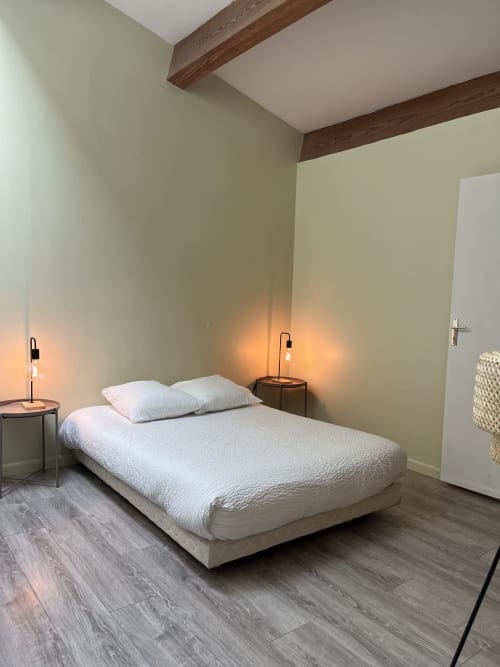 Modern bedroom at La Conciergerie De Franck villa in Boissieres with queen bed, wooden beams, ambient lighting, and