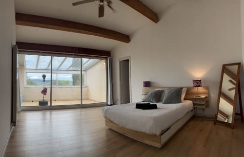 Spacious villa bedroom at La Conciergerie De Franck with bed, exposed beams, glass doors opening to terrace with pool view