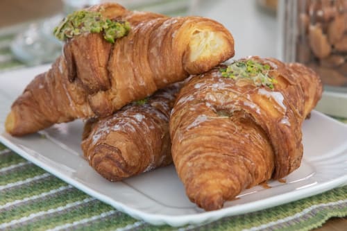 Freshly baked croissants with pistachio topping on white plate at Verdolivo B&B, Sale Marasino