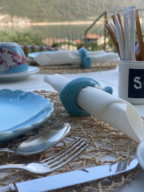 Beach-themed table setting at Verdolivo B&B in Sale Marasino with blue dishes, utensils, napkin holder, and lake view