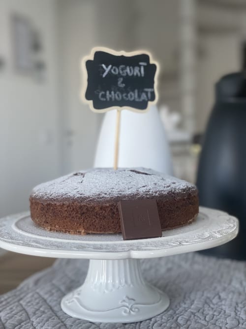 Chocolate yogurt cake on white pedestal stand with chalkboard label at Verdolivo B&B in Sale Marasino, Italy