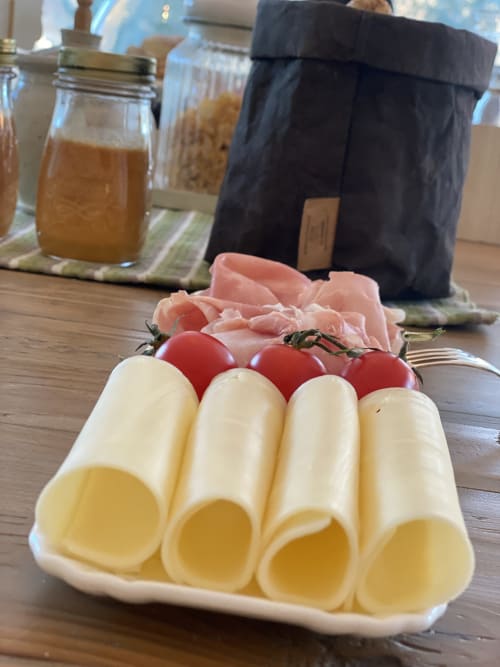 Sliced cheese, prosciutto, and fresh tomatoes on white plate at Verdolivo B&B in Sale Marasino