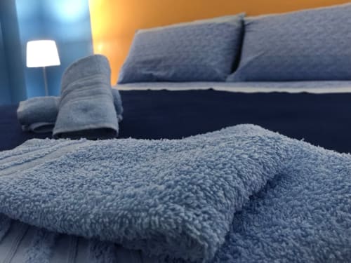 Accogliente coperta blu e cuscini nell'appartamento Stella Marina, rifugio costiero di Porto Empedocle con illuminazione calda