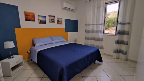 Camera moderna nell'appartamento costiero Stella Marina a Porto Empedocle con arredamento blu e arancione, vista mare, aria condizionata