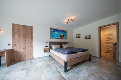 Chambre moderne à la Villa Valtin B&B au Valtin avec lit en bois, sol en ardoise et tableaux de montagne