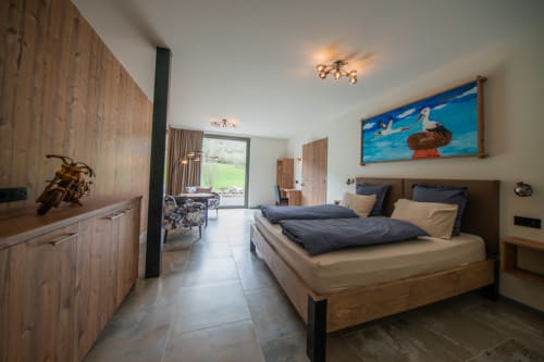 Spacieuse chambre de la Villa Valtin avec lit en bois, vue sur les montagnes, coin salon et accès au balcon au Valtin