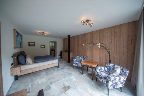 Chambre spacieuse à la Villa Valtin avec lambris, lit, coin salon et vue sur les montagnes du Valtin