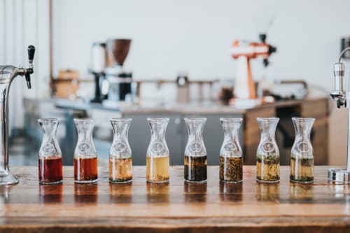 Dégustation de café au Logis des Tourelles à Cognac. Huit tasses en verre avec différents niveaux de torréfaction alignées sur un comptoir en bois.