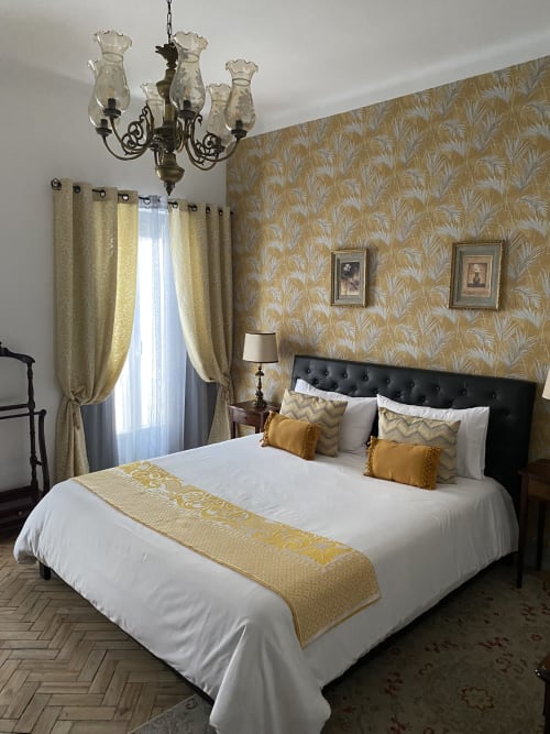 Quarto king superior elegante no Patio Da Villa com papel de parede estampado em dourado, cama estofada preta, lustre e dourado