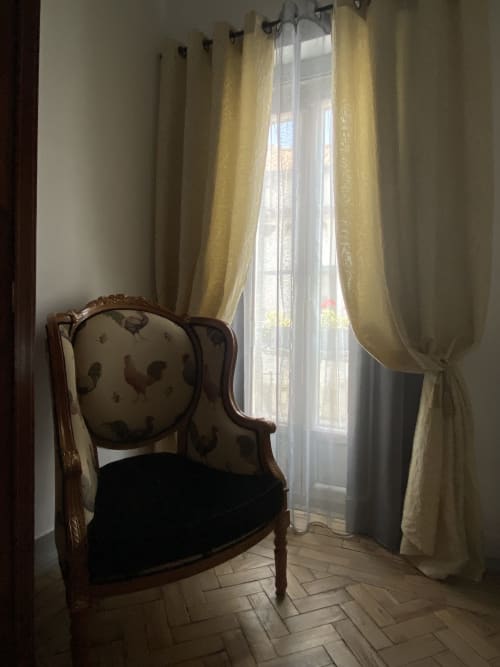 Área de estar elegante na Superior King Room do Patio Da Villa com cadeira estampada de galo e cortinas amarelas com vista para