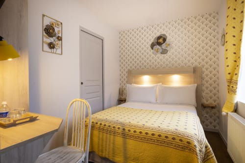 Chambre double standard de l'Hôtel De Lion Sur Mer avec accents jaunes, lit queen-size, bureau et tête de lit crème