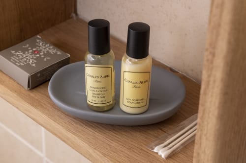 Produits de toilette Charles Aurel Paris sur un plat gris dans la chambre de l'Hôtel De Lion Sur Mer