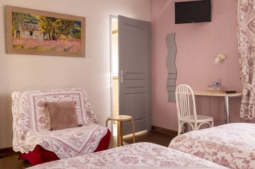 Chambre triple douillette à l'Hôtel De Lion Sur Mer avec décor floral rose, lits jumeaux, bureau et télévision écran plat